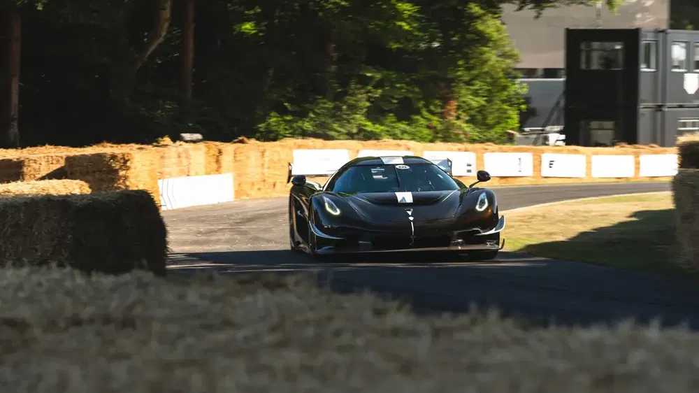 De zwarte Koenigsegg Jesko rijdt snel op een circuit omringd door strobalen.