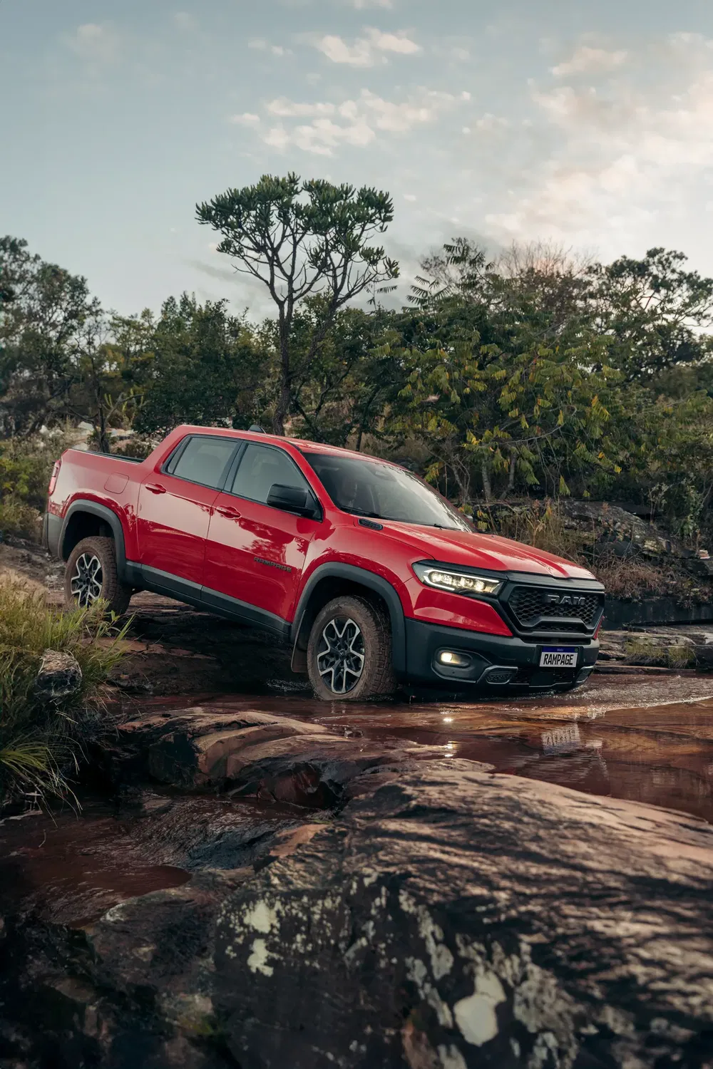 Rode Ram Rampage rijdt over rotsachtig terrein in groene natuurlijke omgeving.
