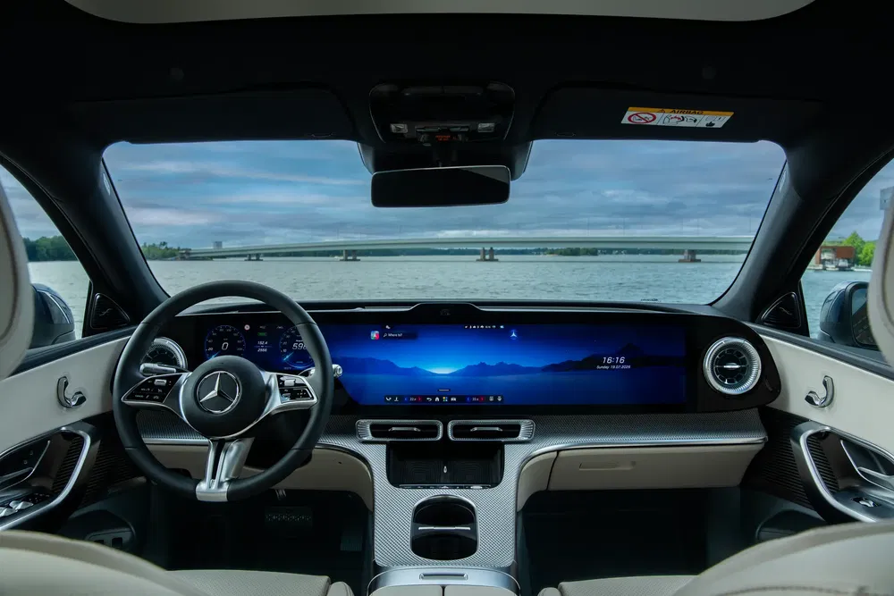 Intérieur d'une Mercedes-Benz avec tableau de bord numérique complet et vue sur un lac.