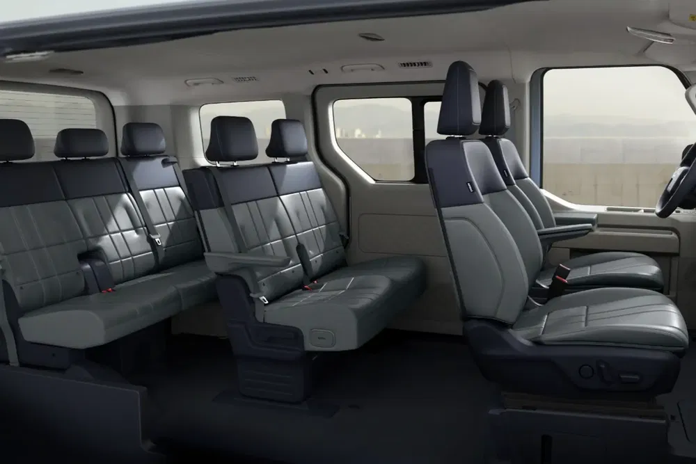 Intérieur spacieux d'un Ford Transit avec sièges en cuir noir et grandes fenêtres.