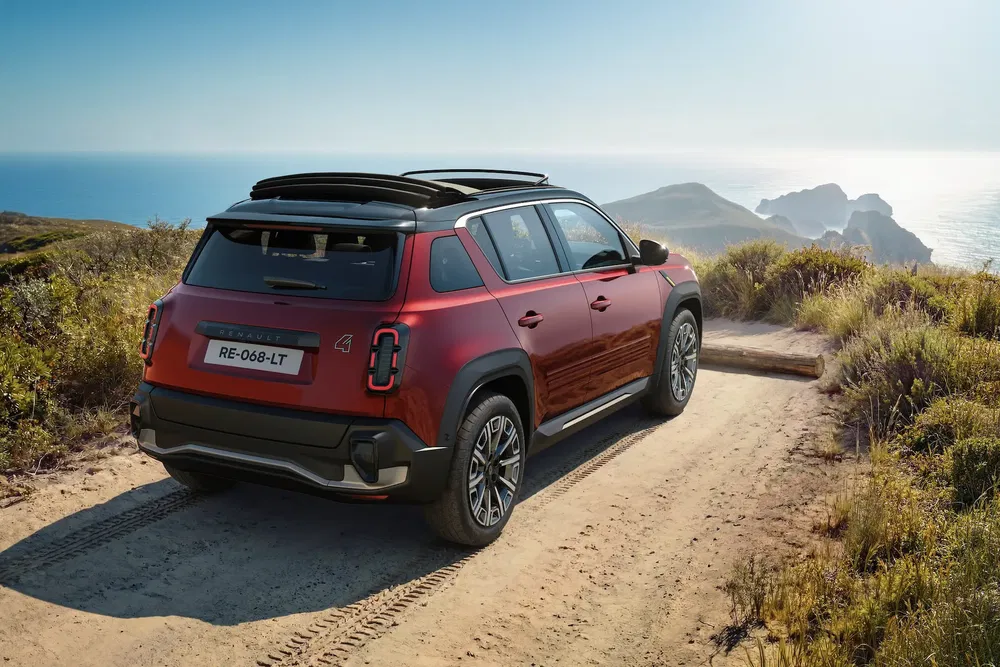 Rode Renault SUV op kustweg met uitzicht op zee en bergen.