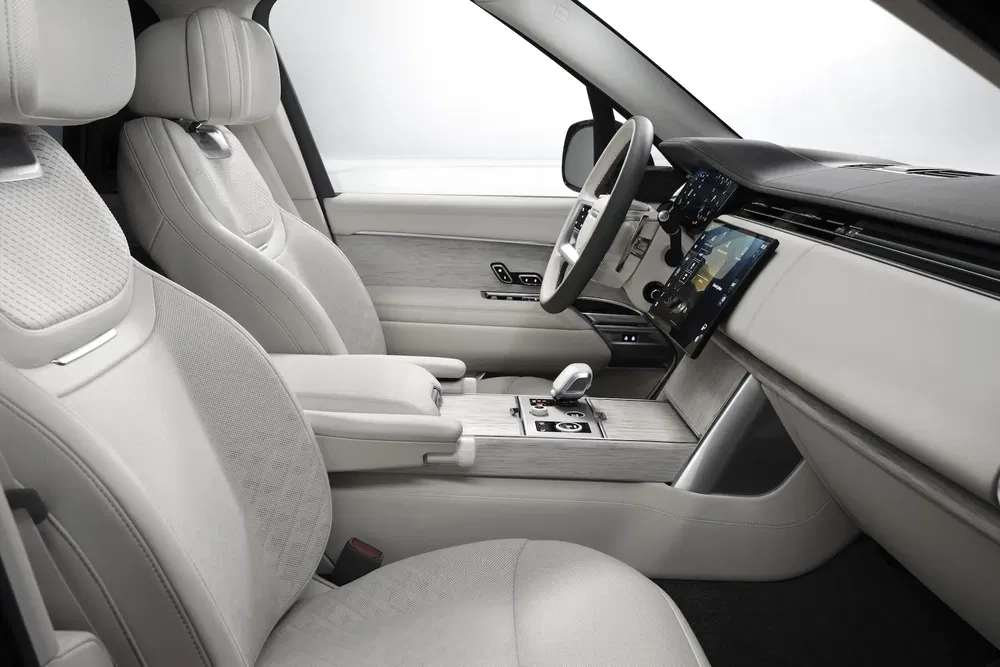 Luxe interieur van een Land Rover Range Rover met witte lederen stoelen en modern dashboard.