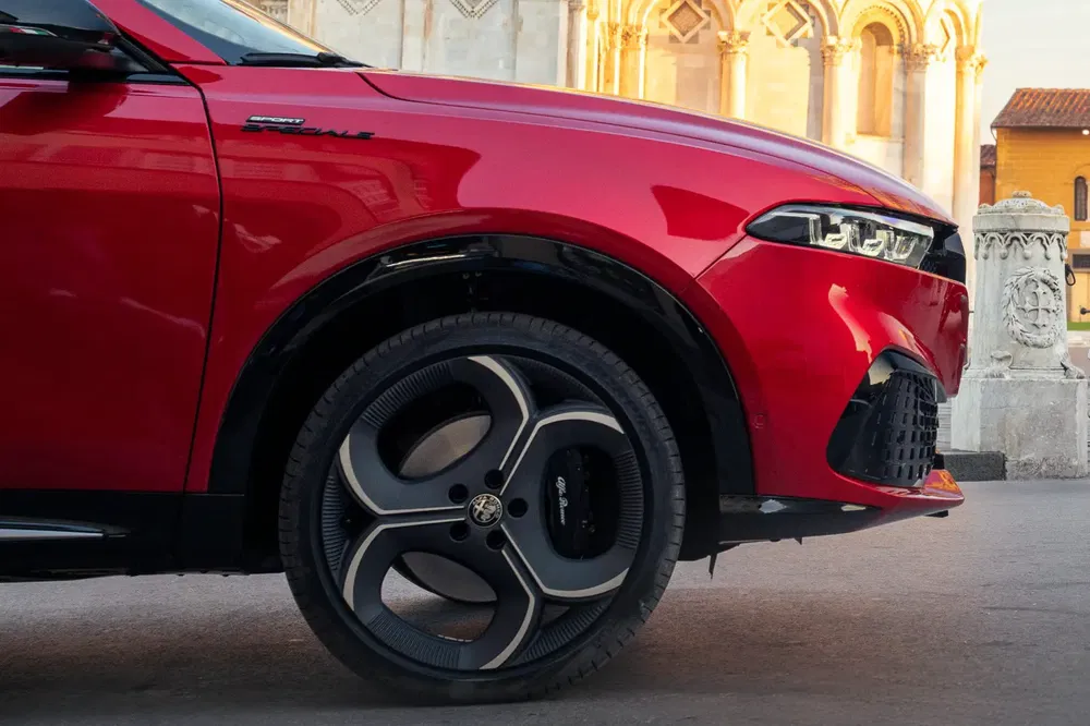 Alfa Romeo Tonale rouge avec des jantes distinctives devant une architecture historique.