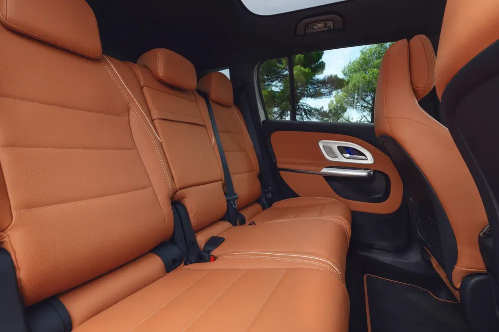 Ruime achterbank met bruine leren stoelen en panoramische ramen in een moderne auto.