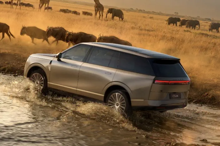 SUV de luxe dans la savane avec des gnous et girafes, traversant une rivière peu profonde.