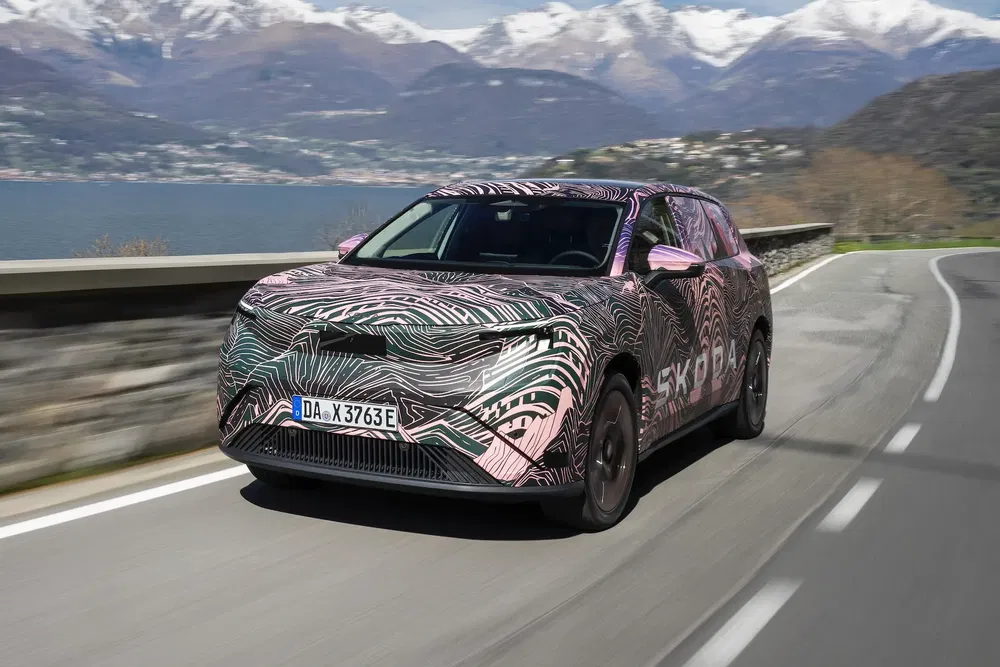 Ge camouflageerde Skoda elektrische prototype op schilderachtige bergweg.
