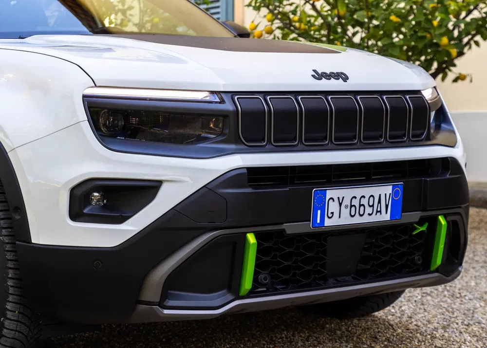 Calandre frontale d'une Jeep blanche avec détails verts et plaque d'immatriculation italienne.