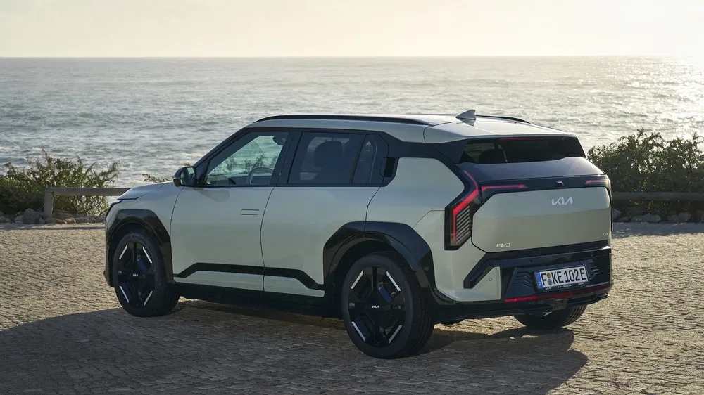 Kia EV9 SUV geparkeerd bij de zee op een zonnige dag, modern en stijlvol ontwerp.