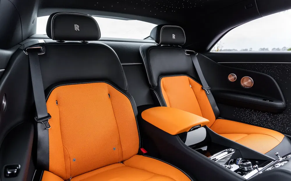 Intérieur luxueux de Rolls-Royce avec sellerie en cuir orange et garniture étoilée.