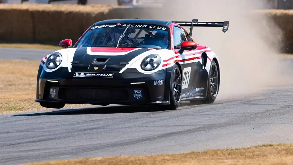Porsche 911 GT3 driftend op circuit, opstuivend stof op de baan.