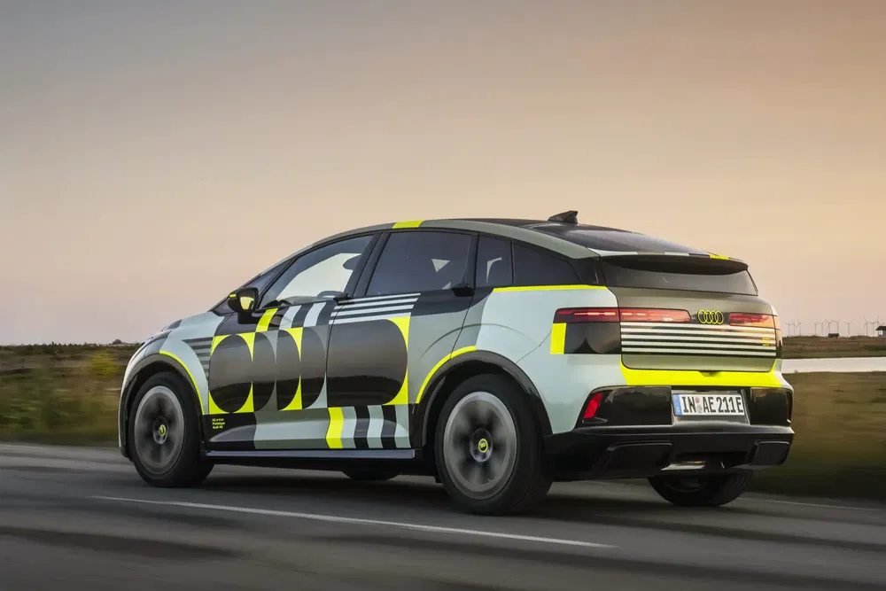 Audi Q6 e-tron électrique camouflée, design futuriste, sur route au crépuscule.