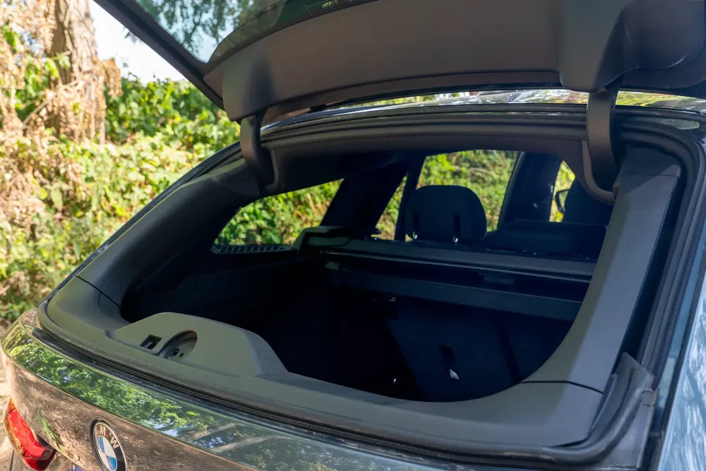 Bagageruimte van BMW met geopende achterklep, groene achtergrond zichtbaar.