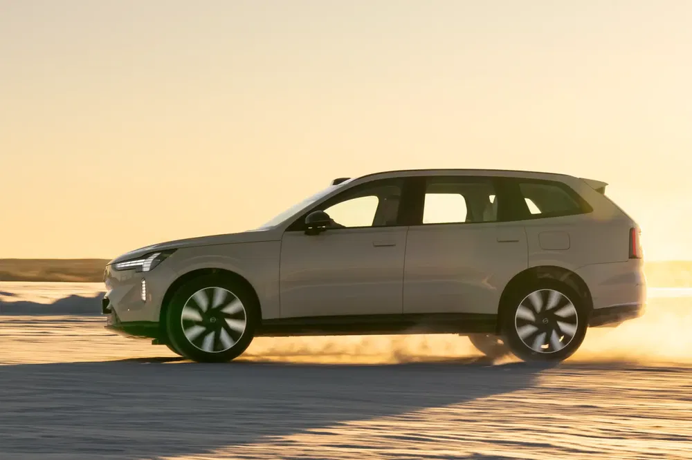 SUV Nio beige roulant sur neige au coucher du soleil, design moderne et élégant.
