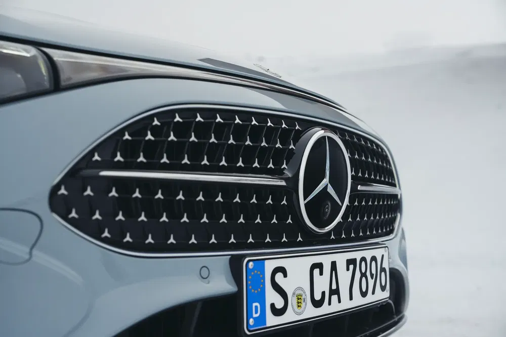 Close-up Mercedes-grille met embleem, Duitse plaat, besneeuwde achtergrond.