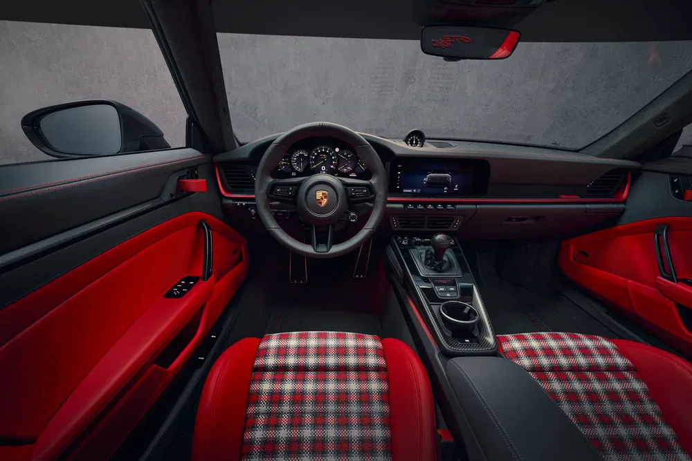 Intérieur de voiture Porsche avec sièges à carreaux rouges et tableau de bord moderne.