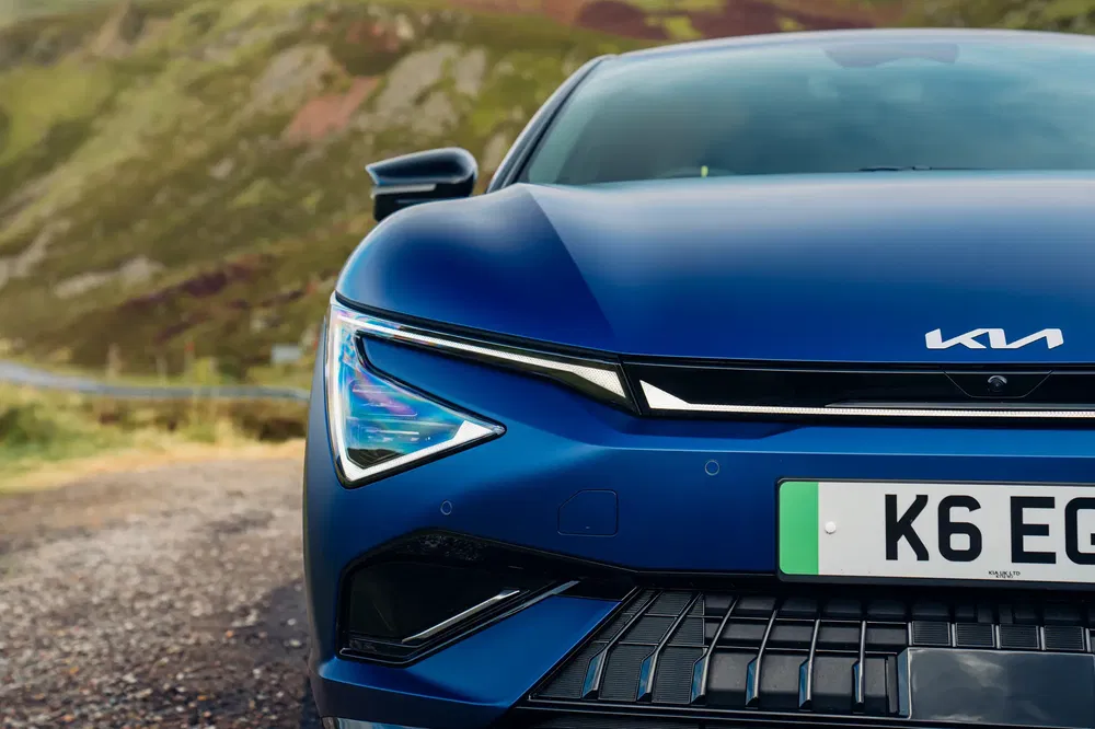 Gros plan avant de la Kia EV6 bleue sur fond de paysage montagneux.