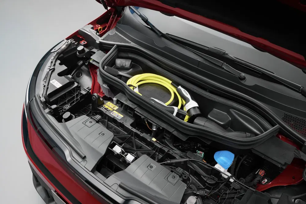Espace de rangement avant d'une voiture électrique avec câbles de recharge visibles.