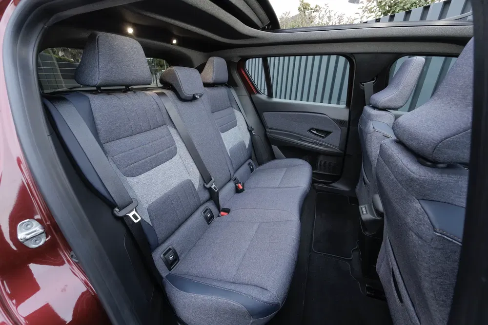 Intérieur arrière spacieux d'une voiture moderne avec sièges en tissu gris et ceintures de sécurité.