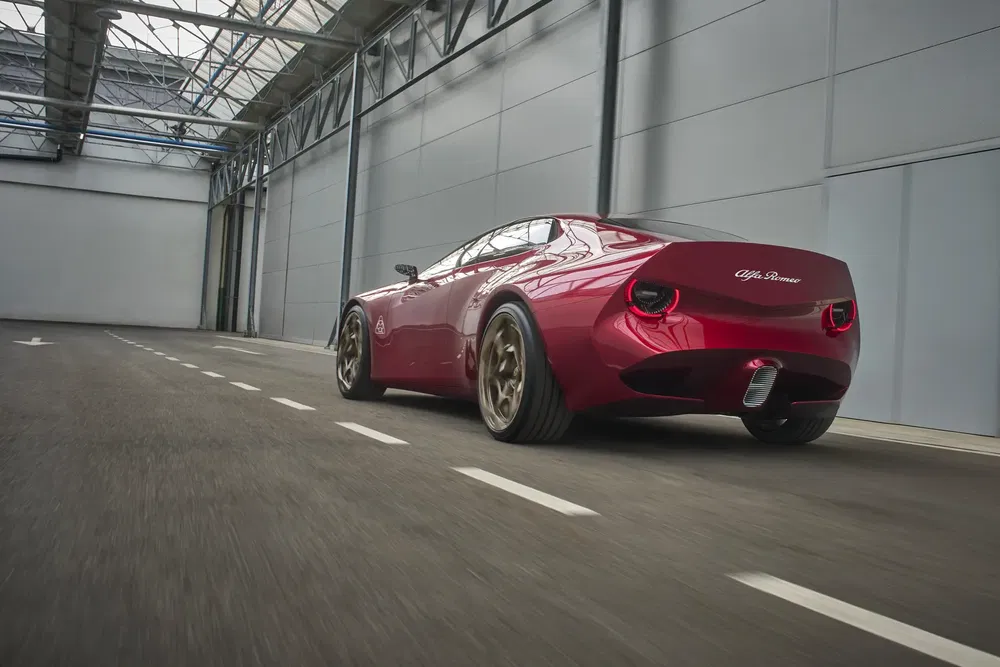 Alfa Romeo rouge dans un entrepôt, design élégant et lignes aérodynamiques distinctives.