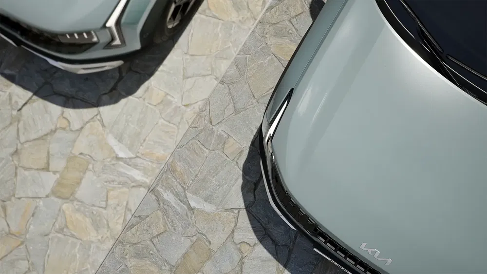 Vue aérienne de deux voitures Kia grises sur un sol pavé.