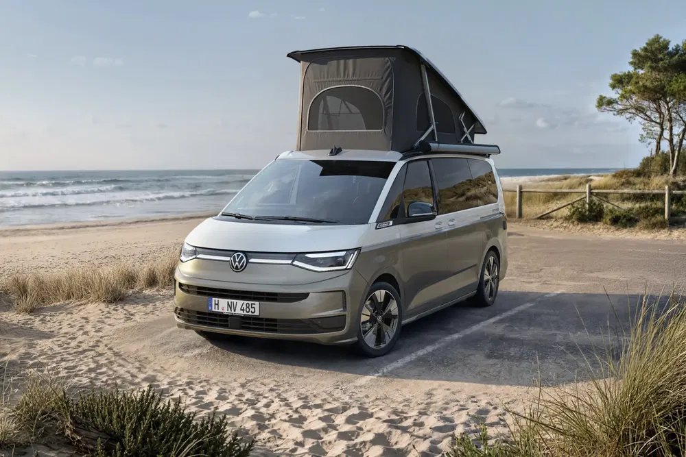 Volkswagen California 2023 avec toit surélevé, stationné sur une plage pittoresque.