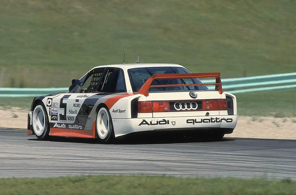 Audi 90 Quattro IMSA GTO en course sur circuit, livrée Audi Sport distinctive.