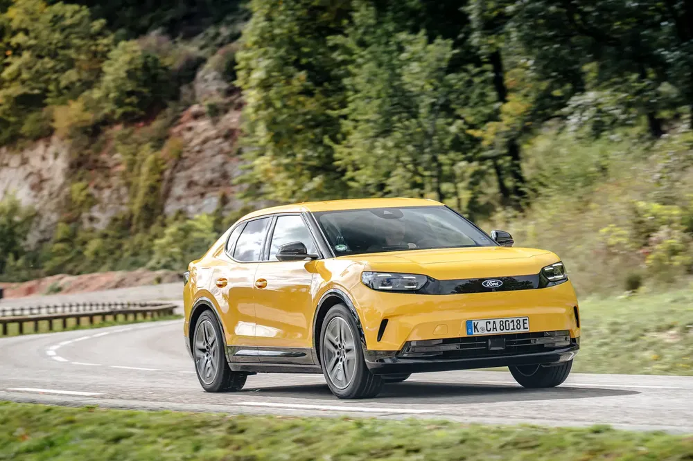 Ford Explorer jaune 2023 roulant sur une route sinueuse entourée de verdure.