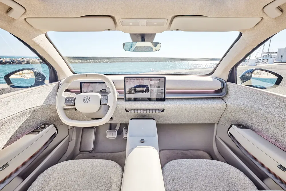 Intérieur moderne de la Volkswagen ID avec écran tactile et volant multifonctions, vue sur la mer.