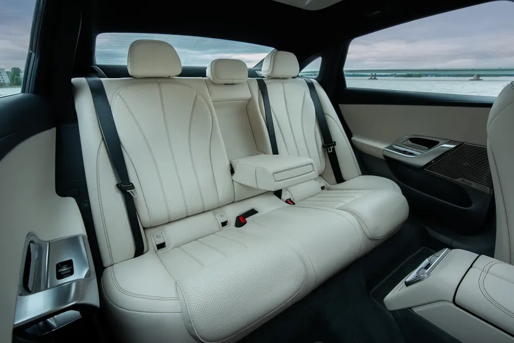Intérieur arrière de luxe d'une BMW i7 avec sièges en cuir blanc et accoudoir central.