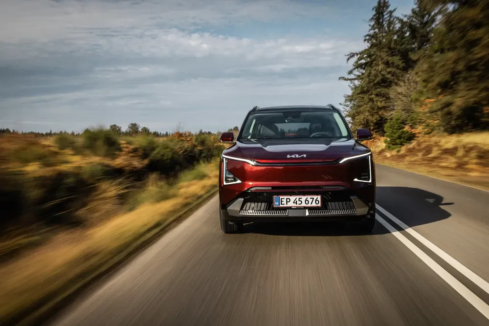 Kia électrique en mouvement sur une route, design avant moderne et élégant.
