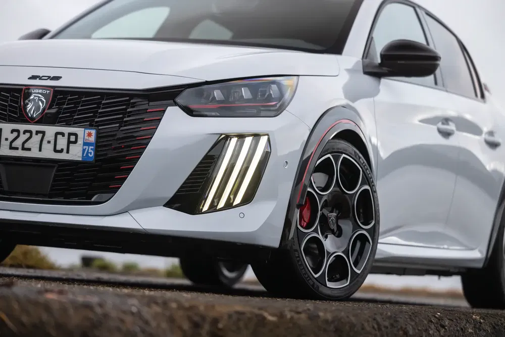 Vue avant d'une Peugeot 208 blanche avec des phares LED distinctifs et jantes stylisées.