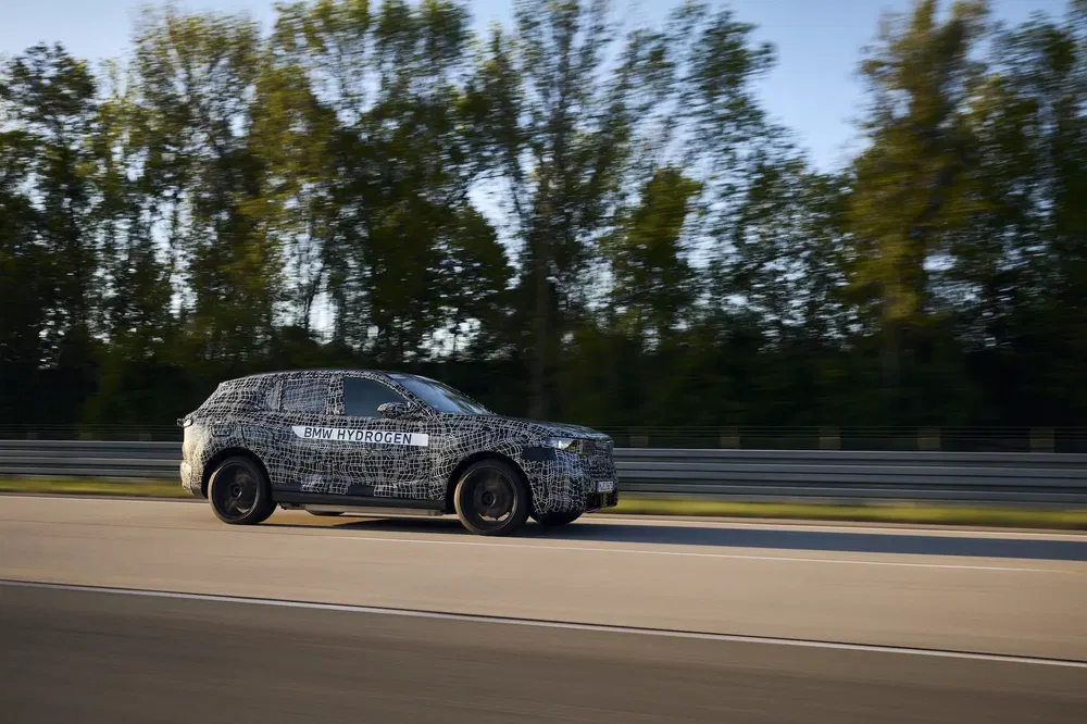 BMW Hydrogène en camouflage sur autoroute, forêt en arrière-plan, test de conduite.