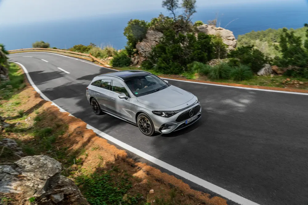 Mercedes-Benz sur route côtière sinueuse avec vue sur mer et paysage verdoyant.