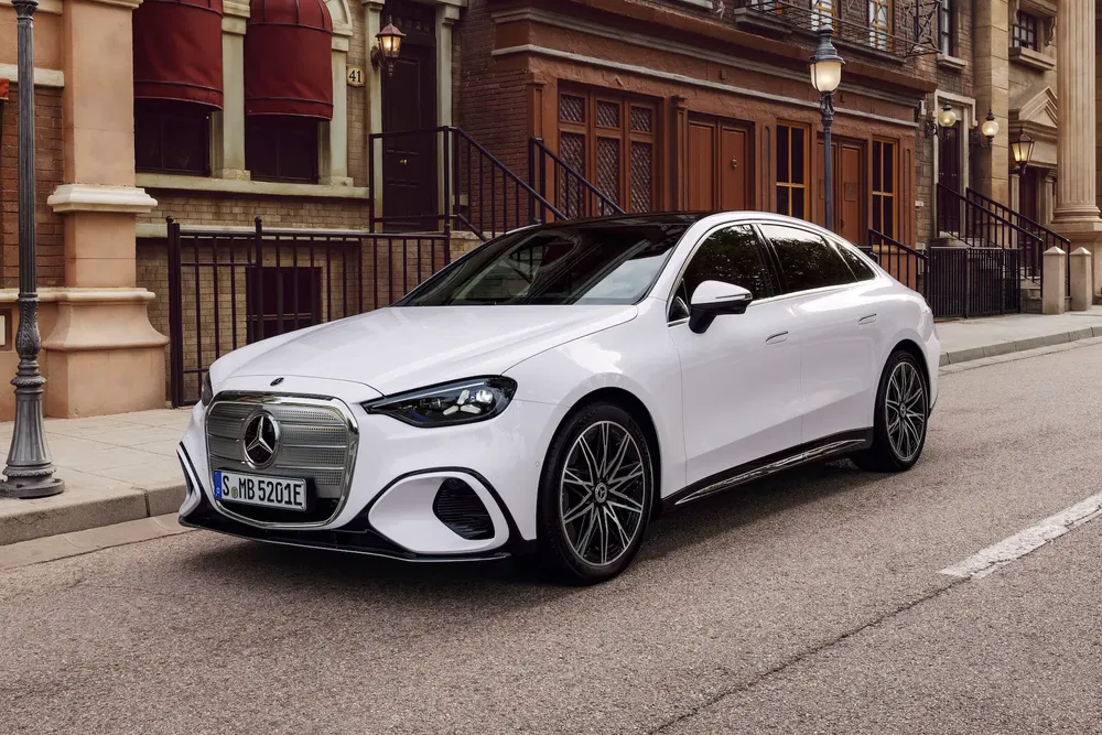 Mercedes-Benz E-Class blanche stationnée dans une rue urbaine bordée d'immeubles.