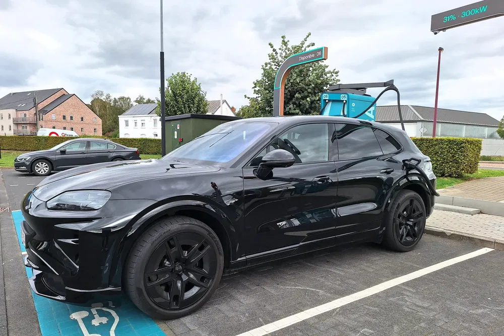 Porsche Macan électrique noir chargeant à une station de recharge rapide moderne.