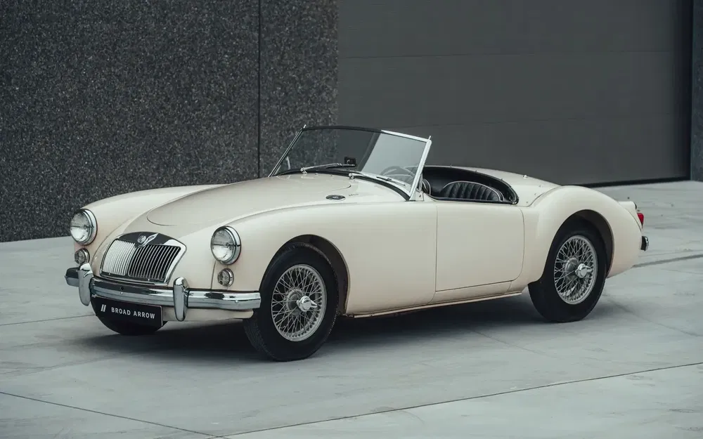 Voiture classique MG Cream MGA 1600 décapotable, stationnée devant une façade grise moderne.