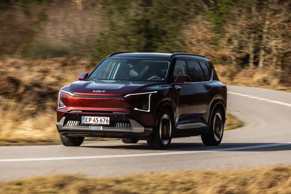 SUV Kia en mouvement sur une route de campagne, design moderne et dynamique.