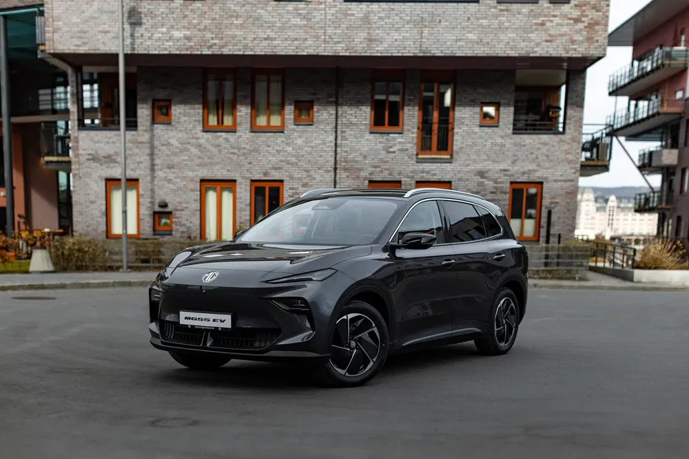 SUV électrique MG intrigant devant un bâtiment moderne en brique.
