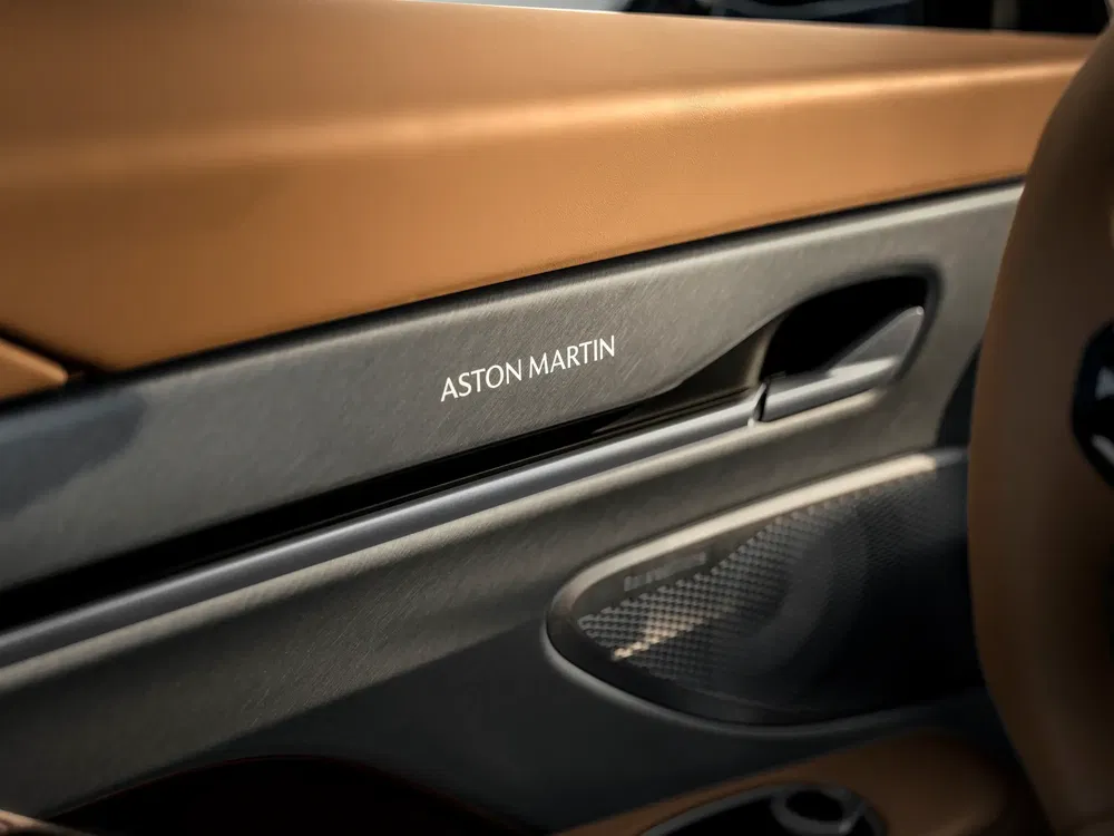 Intérieur luxueux d'une voiture Aston Martin avec des détails en cuir et logo visible.