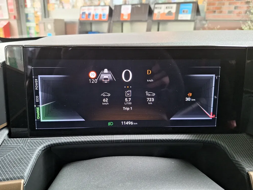 Tableau de bord numérique d'une voiture affichant la vitesse actuelle, consommation et distance parcourue.