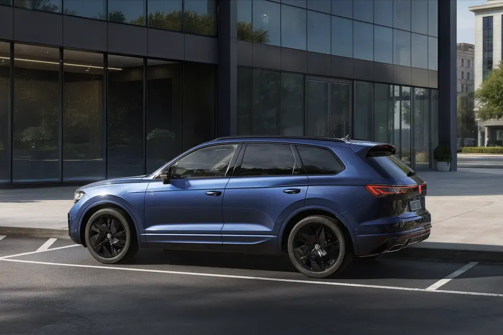 Blauwe Volkswagen Touareg SUV geparkeerd voor een modern gebouw met glazen ramen.