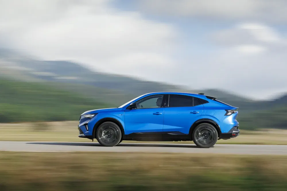Renault Arkana bleu roulant sur une route panoramique de campagne.