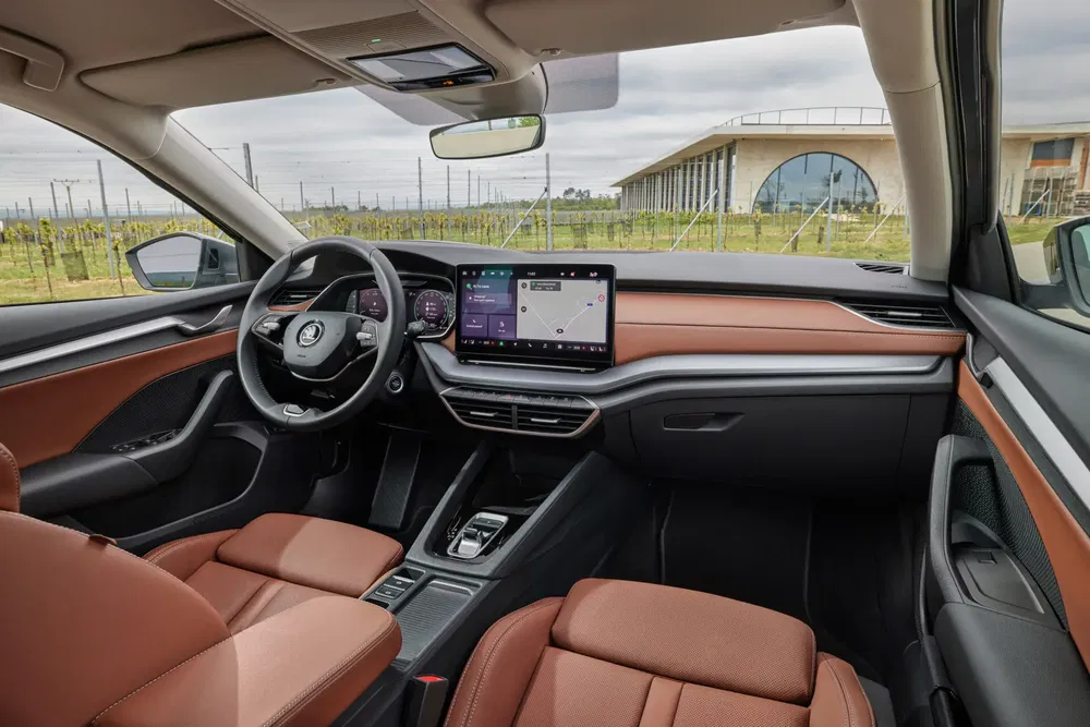 Intérieur de la Skoda Enyaq 2024 avec écran tactile moderne et finitions en cuir brun.