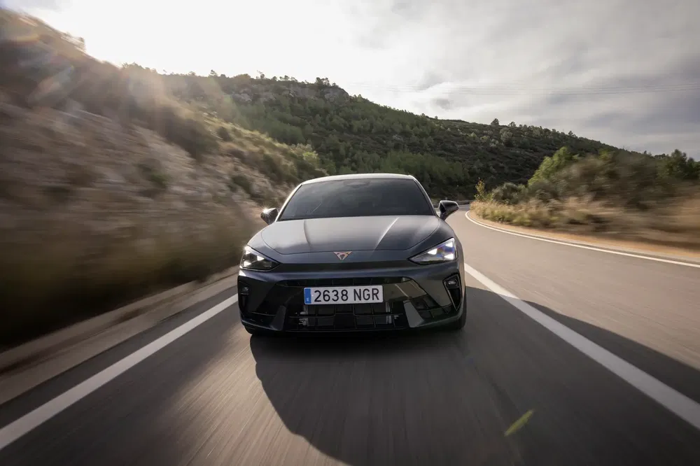 De Cupra DarkRebel rijdt op een bochtige bergweg onder een bewolkte hemel.