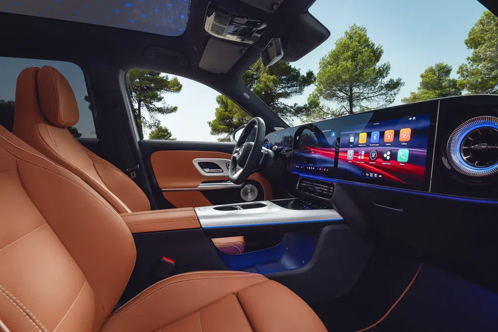 Luxe interieur van een Mercedes-Benz met bruine leren stoelen en modern multimediascherm.