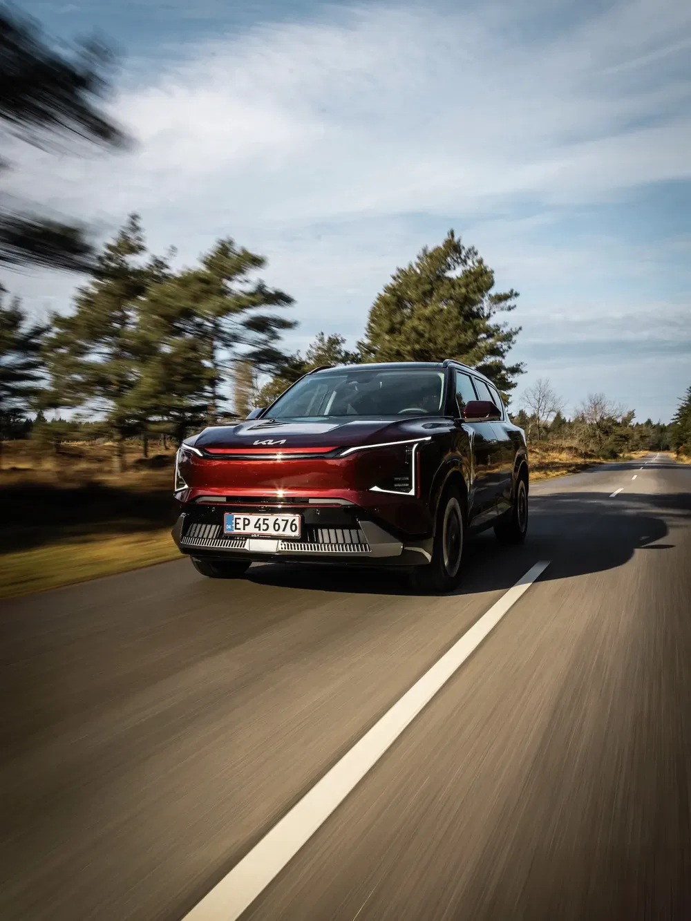 SUV Kia moderne roulant sur une route entourée de paysages naturels et ciel dégagé.