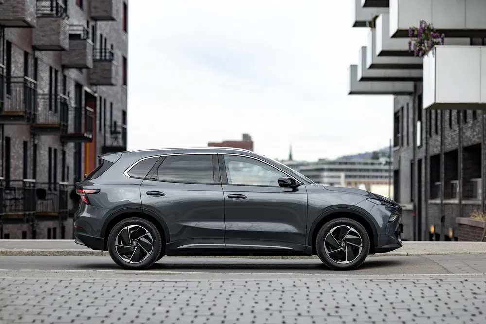 SUV moderne, gris, stationné dans un quartier urbain moderne avec bâtiments en briques.