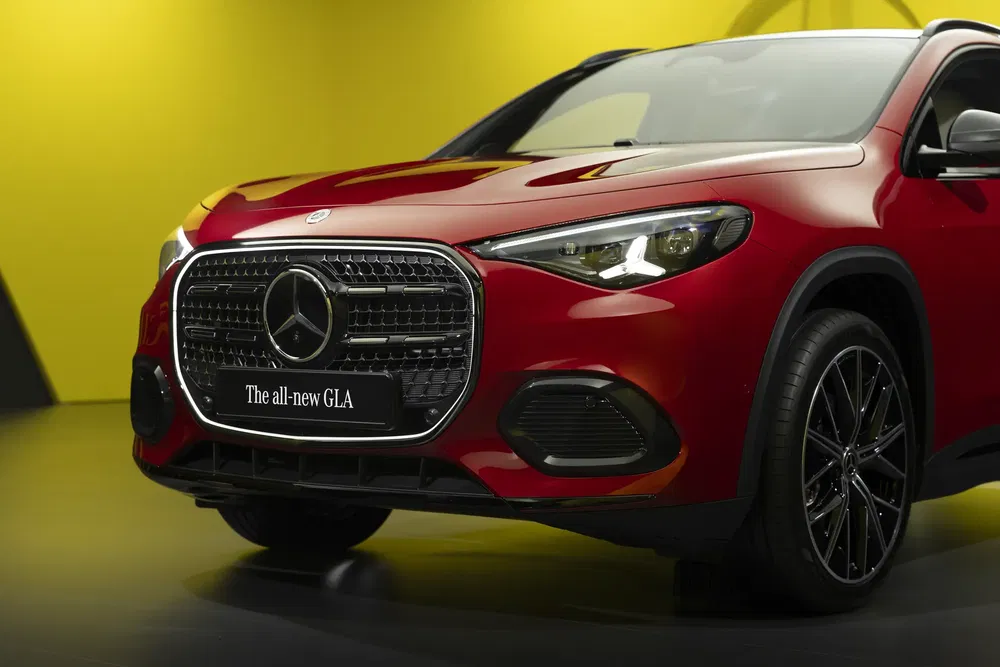 Mercedes-Benz GLA rouge avec calandre imposante, phares LED, fond jaune.