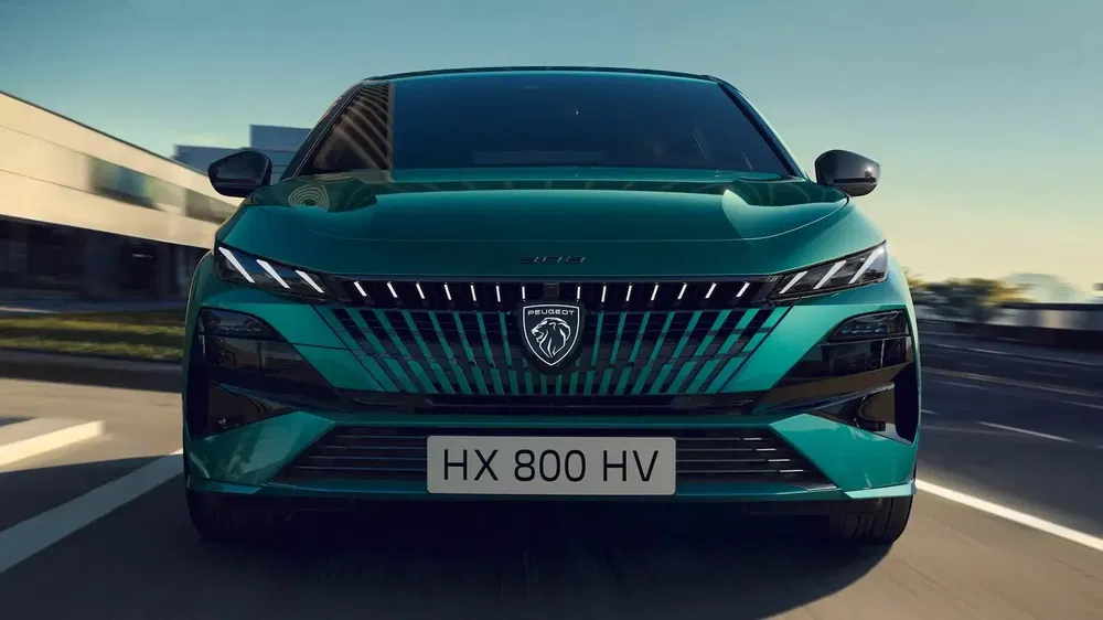 Vooraanzicht van de groene Peugeot 308 op een zonnige weg.