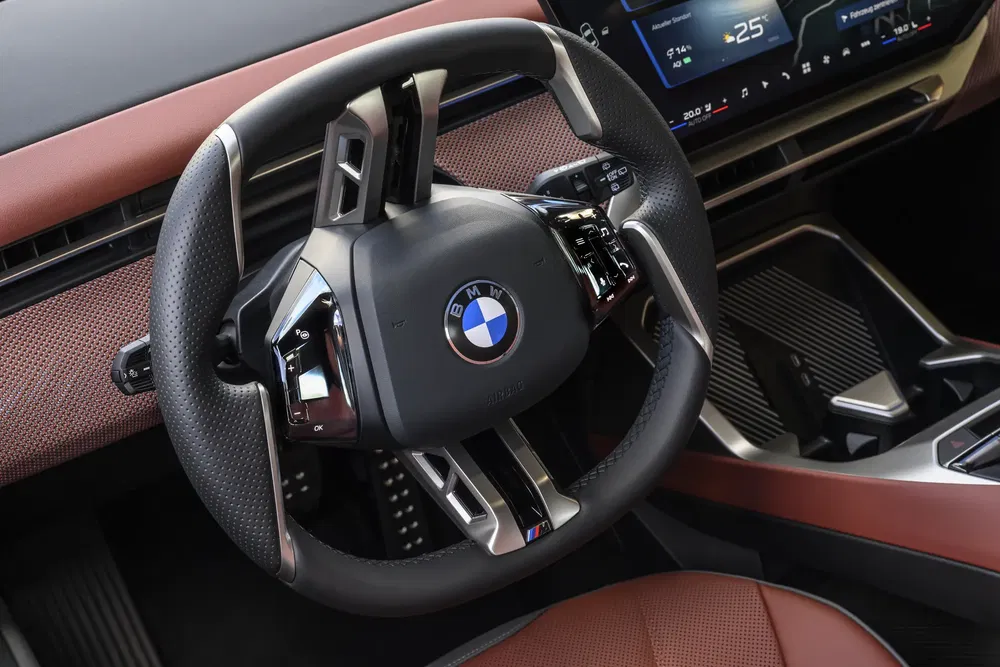 Volant BMW moderne avec écran numérique, intérieur bicolore en cuir marron.